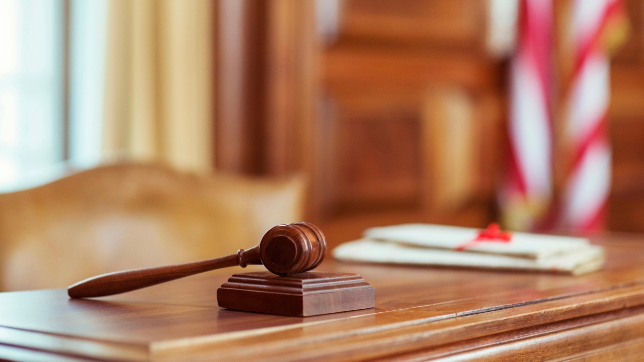 A gavel sitting on a judge's desk in a courtroom A gavel sitting on a judge's desk in a courtroom