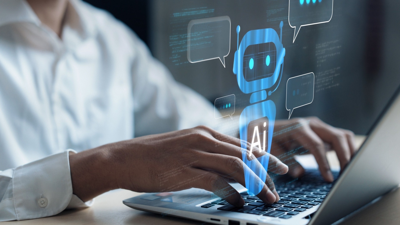 Person types on a laptop keyboard; a robot labeled "Ai" floats above the keyboard Person types on a laptop keyboard; a robot labeled "Ai" floats above the keyboard