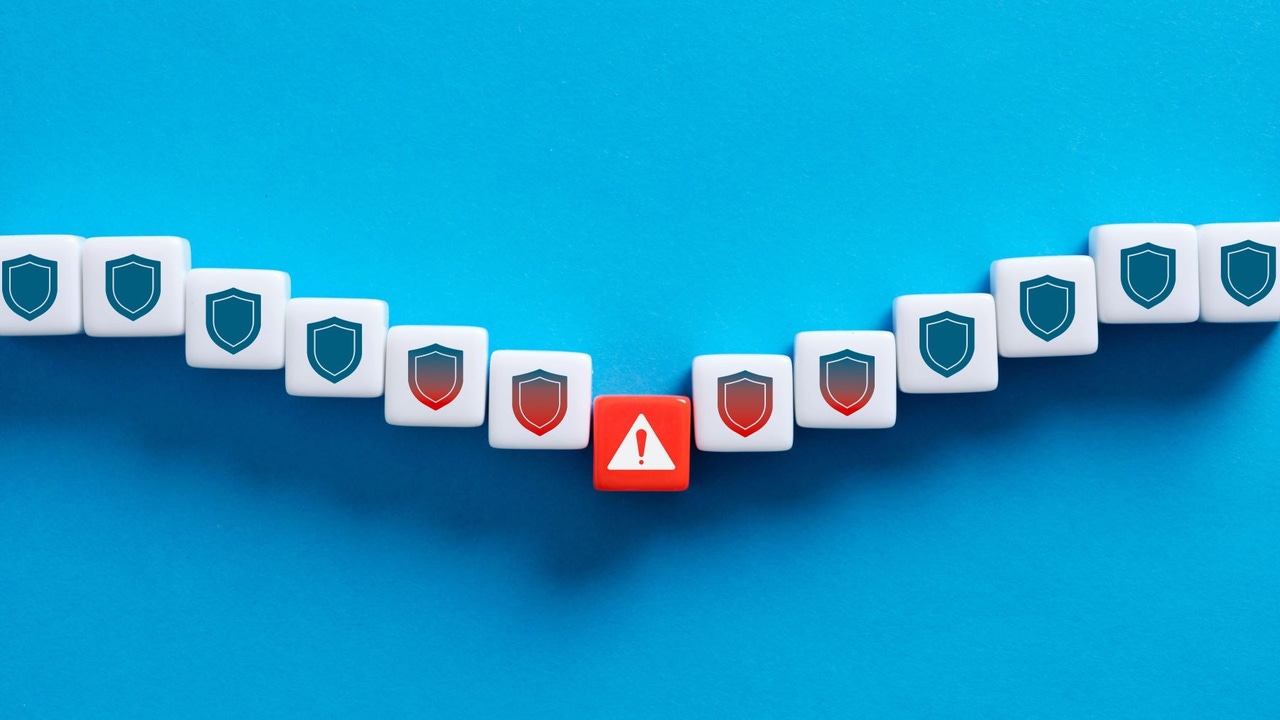 Tiles with a shield, indicating security; they dip and in the middle is an exclamation point, then the shields rise again; the background is blue Tiles with a shield, indicating security; they dip and in the middle is an exclamation point, then the shields rise again; the background is blue