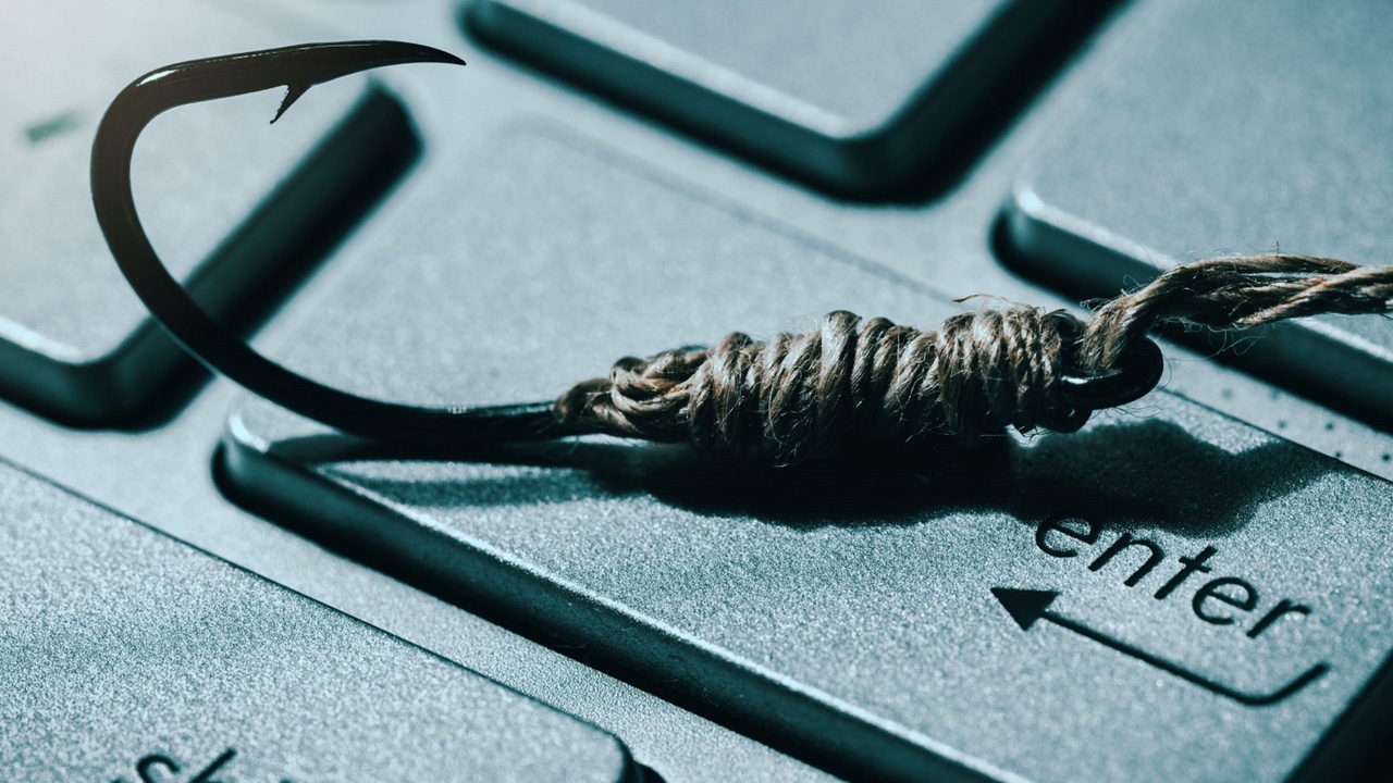 Fishing hook wrapped in string lying on top of the "enter" key of a computer keyboard Fishing hook wrapped in string lying on top of the "enter" key of a computer keyboard