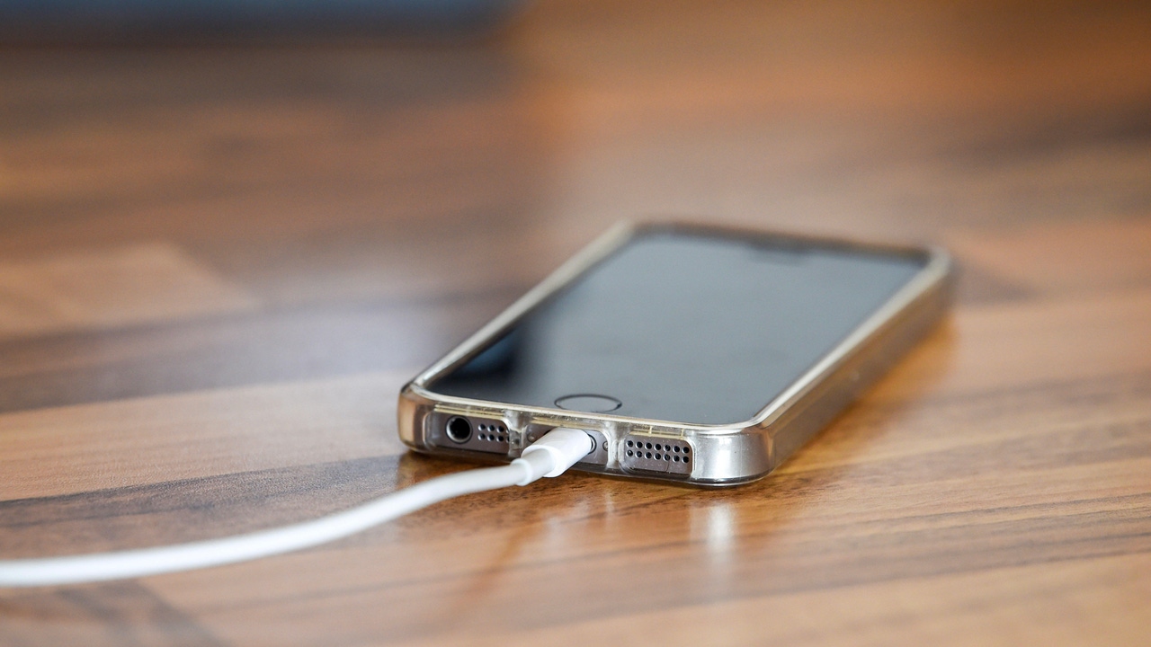 An iPhone charging on a wooden table An iPhone charging on a wooden table