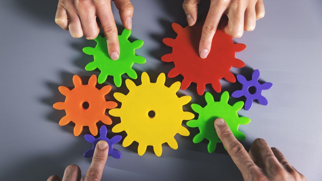 Multicolored hands rotating multiple different-colored gears. Multicolored hands rotating multiple different-colored gears.