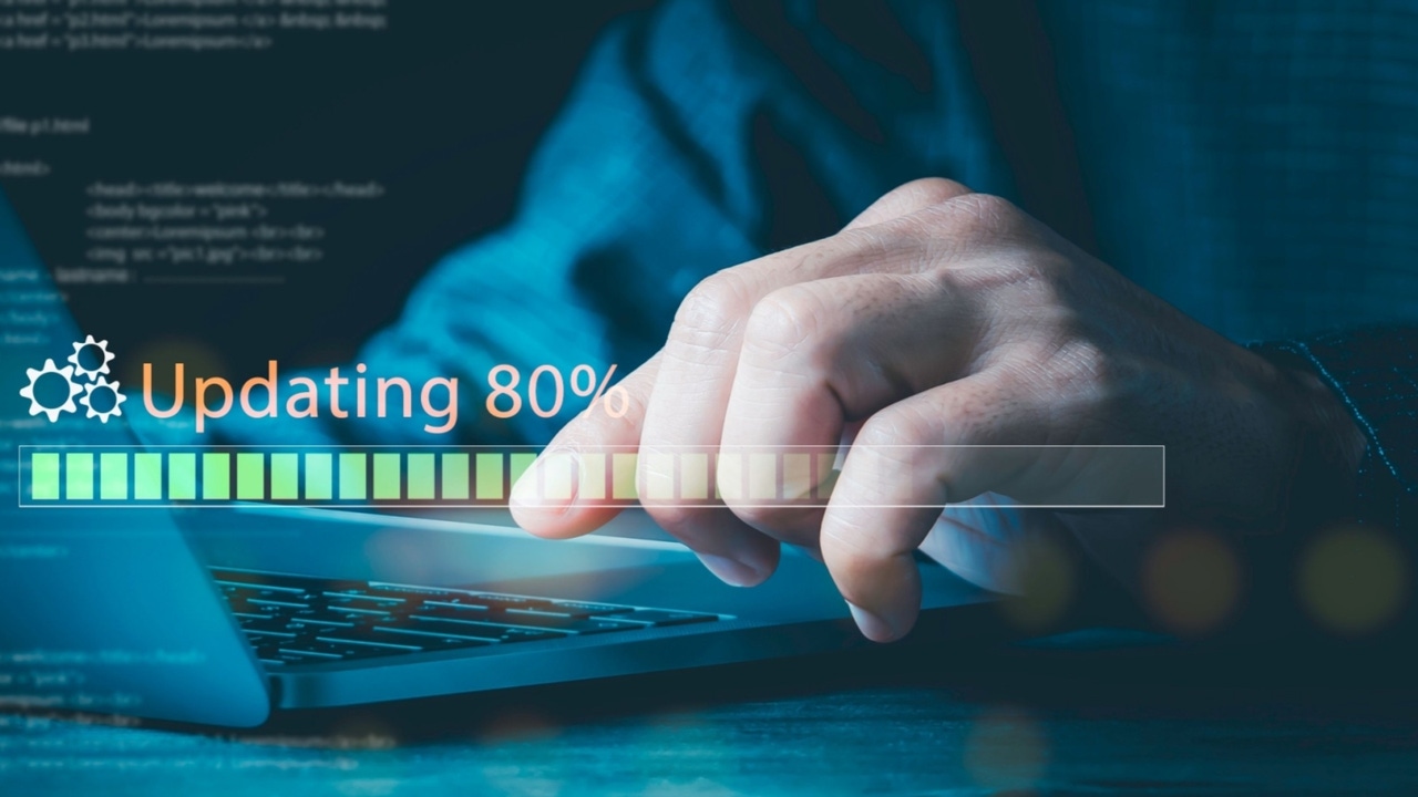 Hand of a person sitting at a computer about to hit a key on the keyboard with the text "Updating 80%" Hand of a person sitting at a computer about to hit a key on the keyboard with the text "Updating 80%"